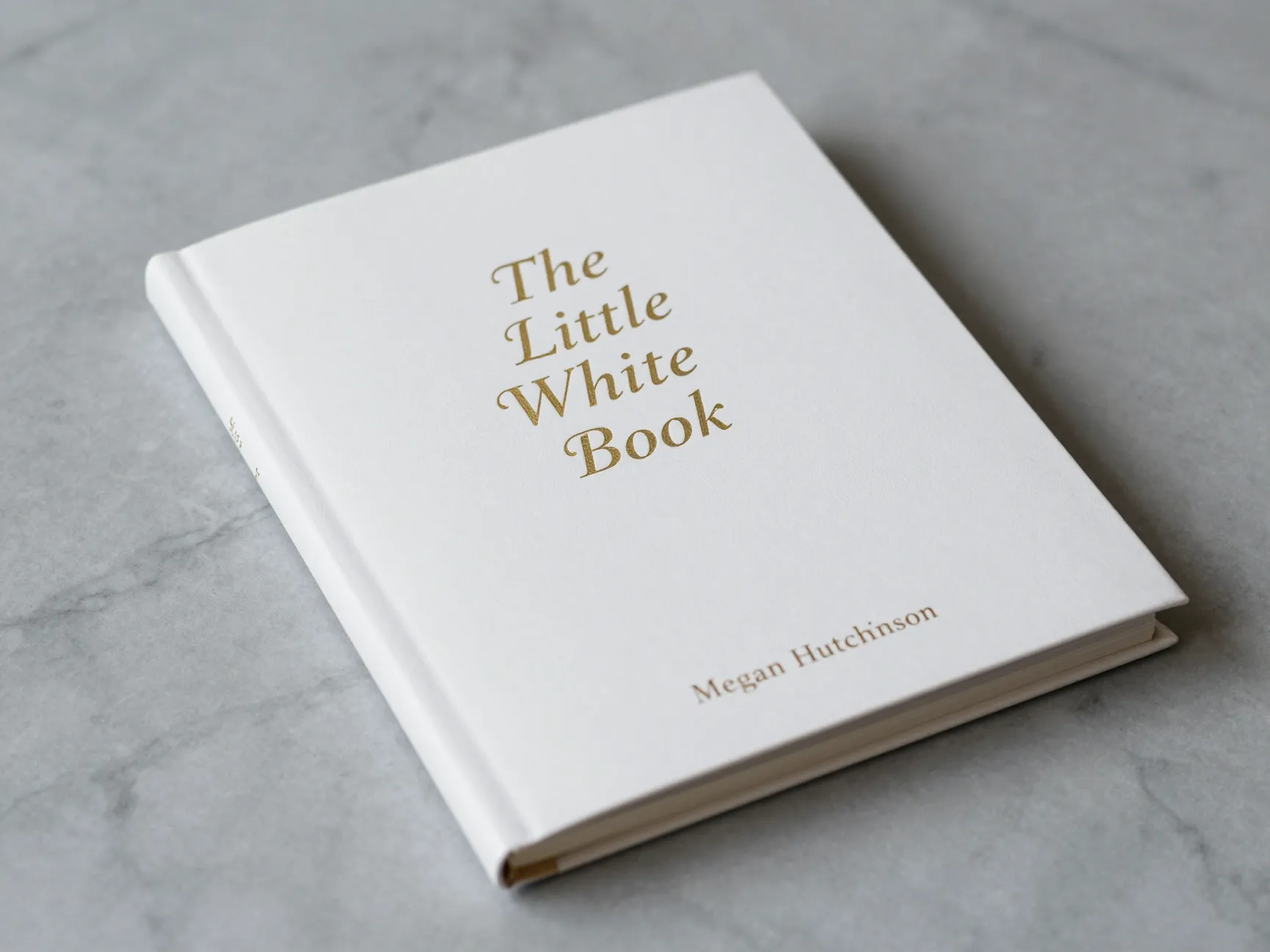 Little white book wedding planner with dual language options on marble
