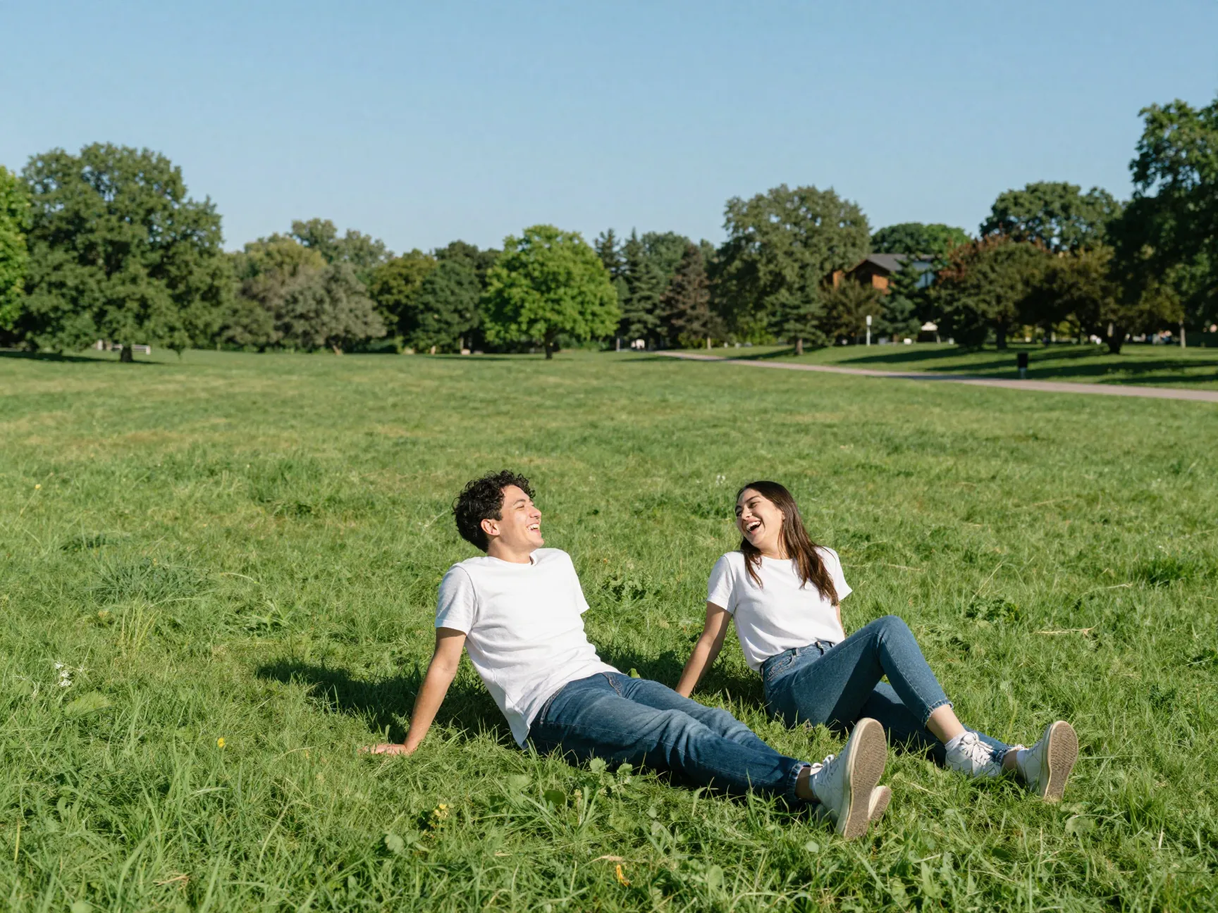 Couple laughing on open green field in relaxed sunny park setting