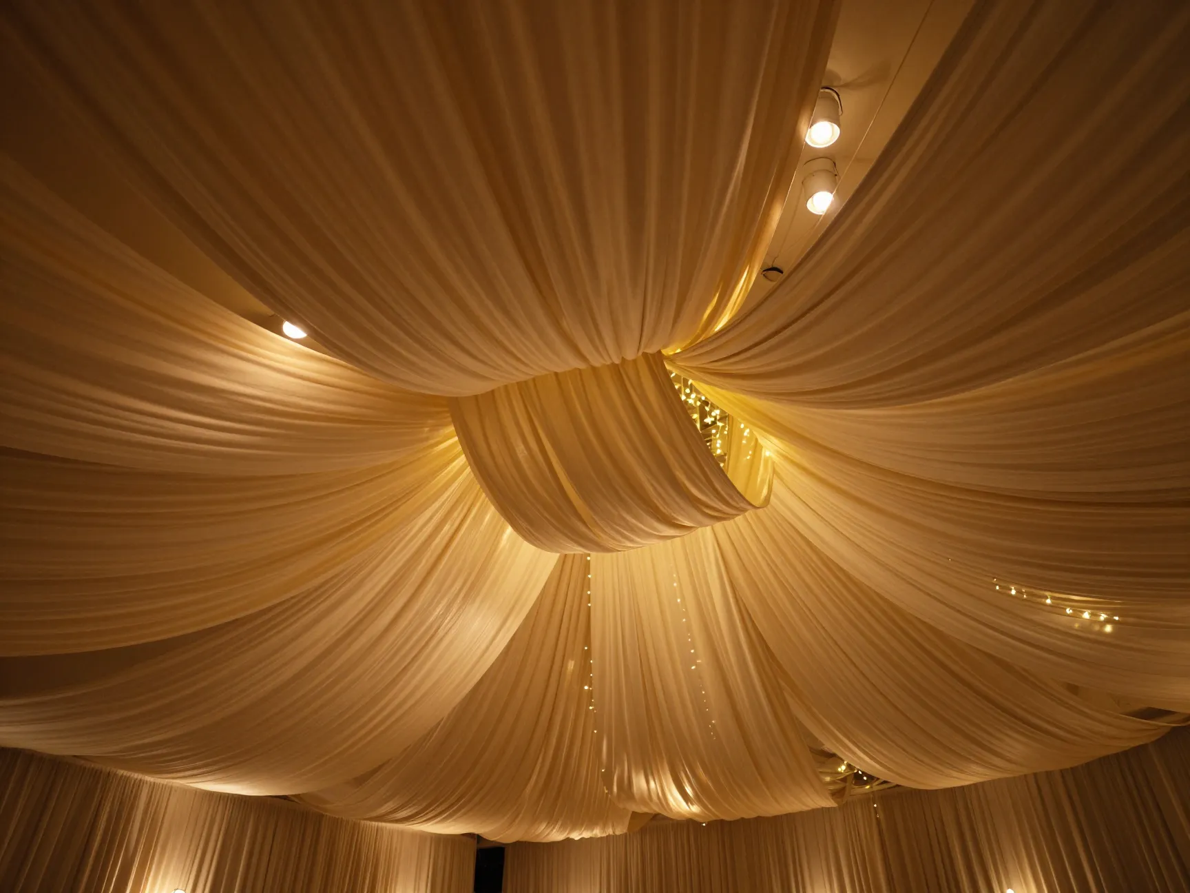 Dramatic draped fabric canopy with warm amber uplighting