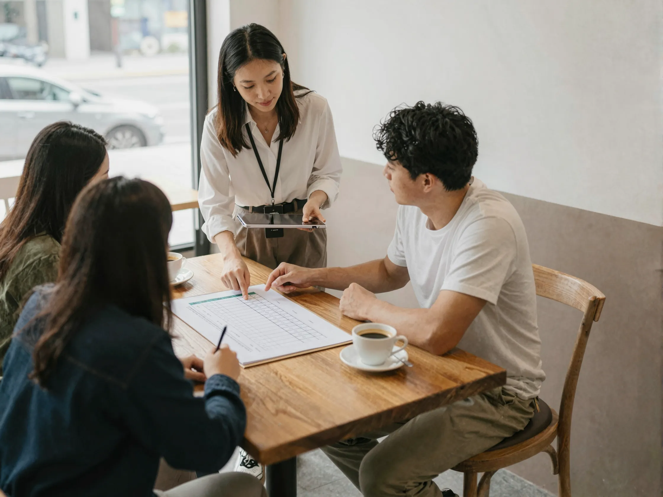 Professional wedding planner reviewing timeline with couple in cafe