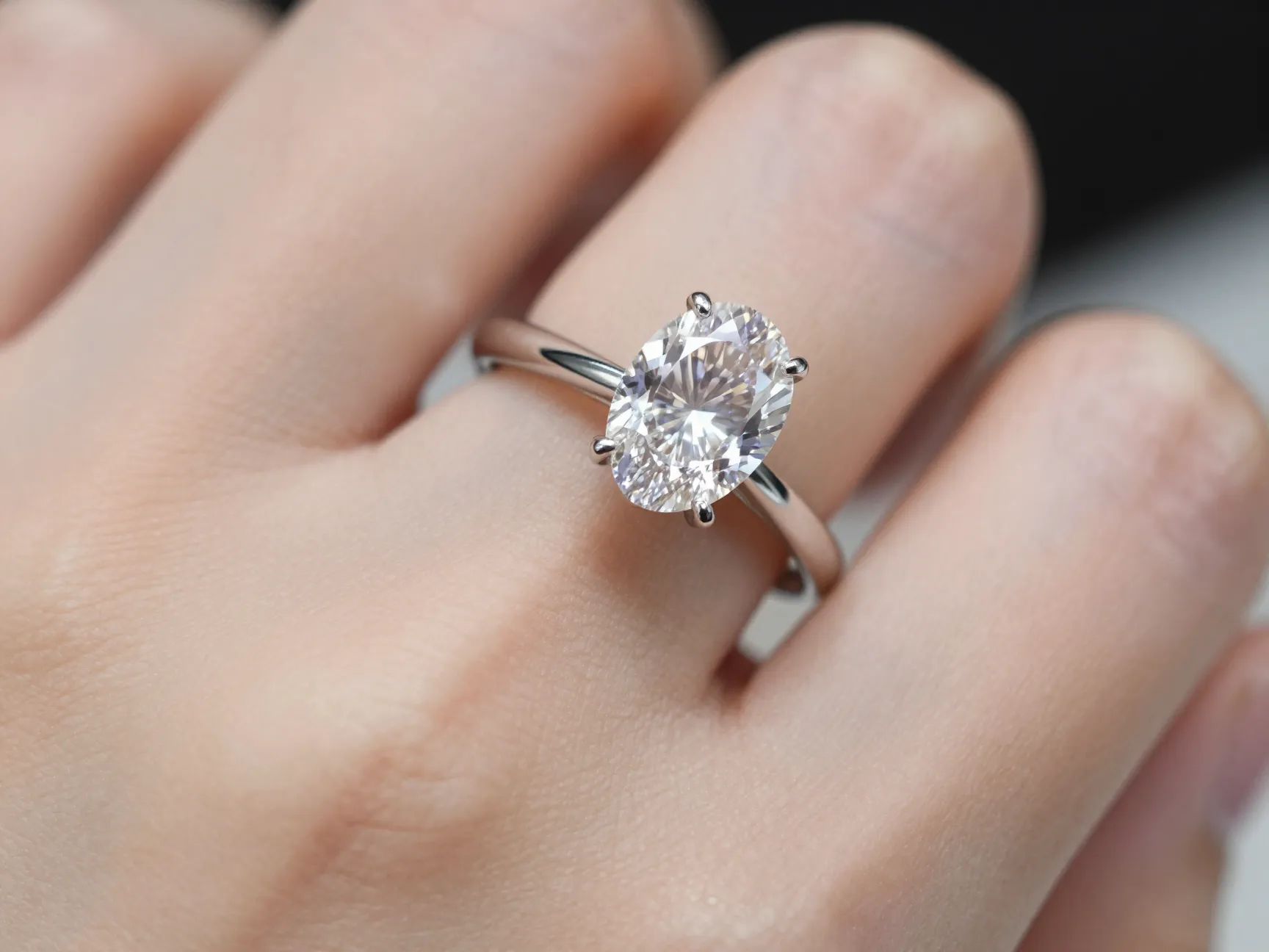 Elongated oval diamond ring on finger in elegant setting