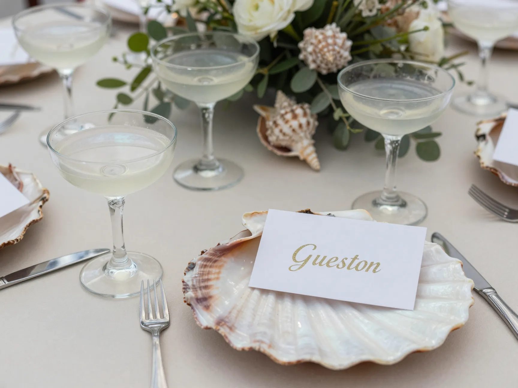 Pearlescent seashell coupe glasses and escort card on table