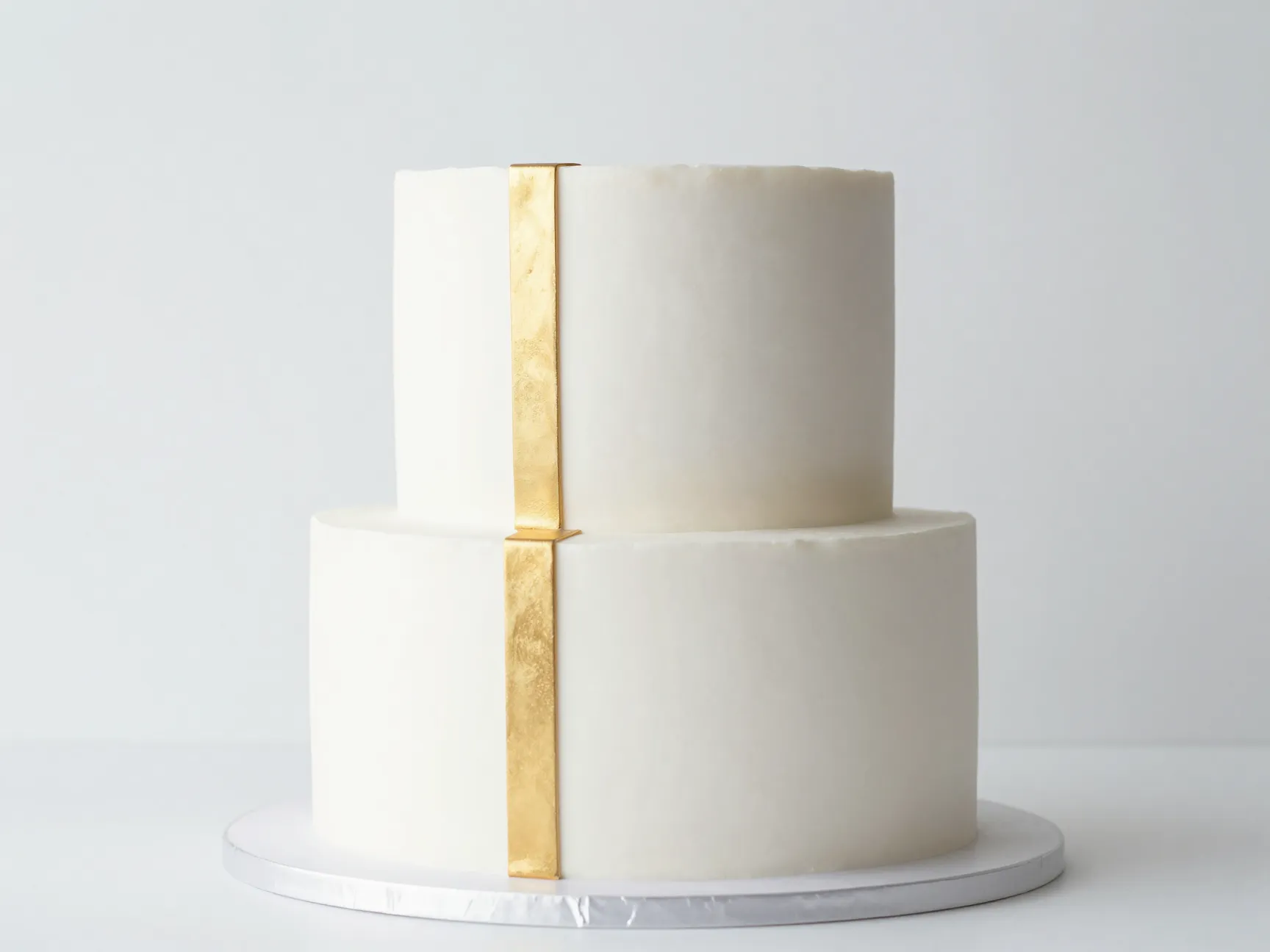Minimalist white fondant cake with single gold geometric stripe