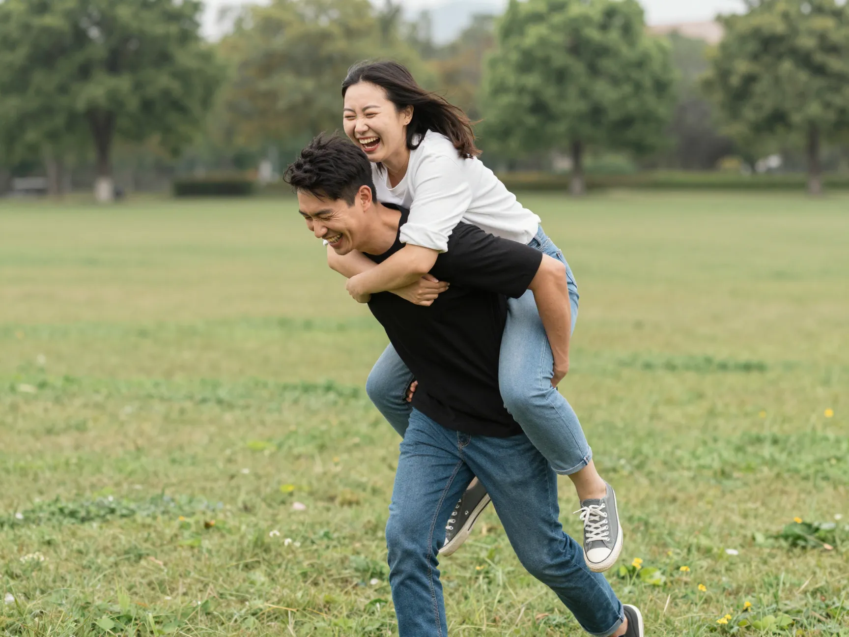 Laughing couple on piggyback ride in flat open park location