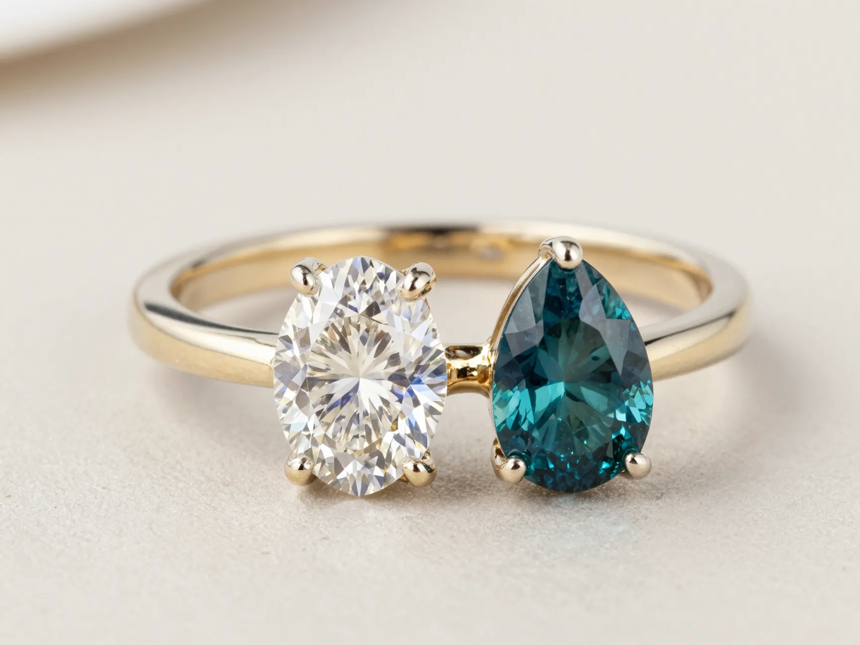 Toi et moi ring oval diamond pear teal sapphire on neutral background