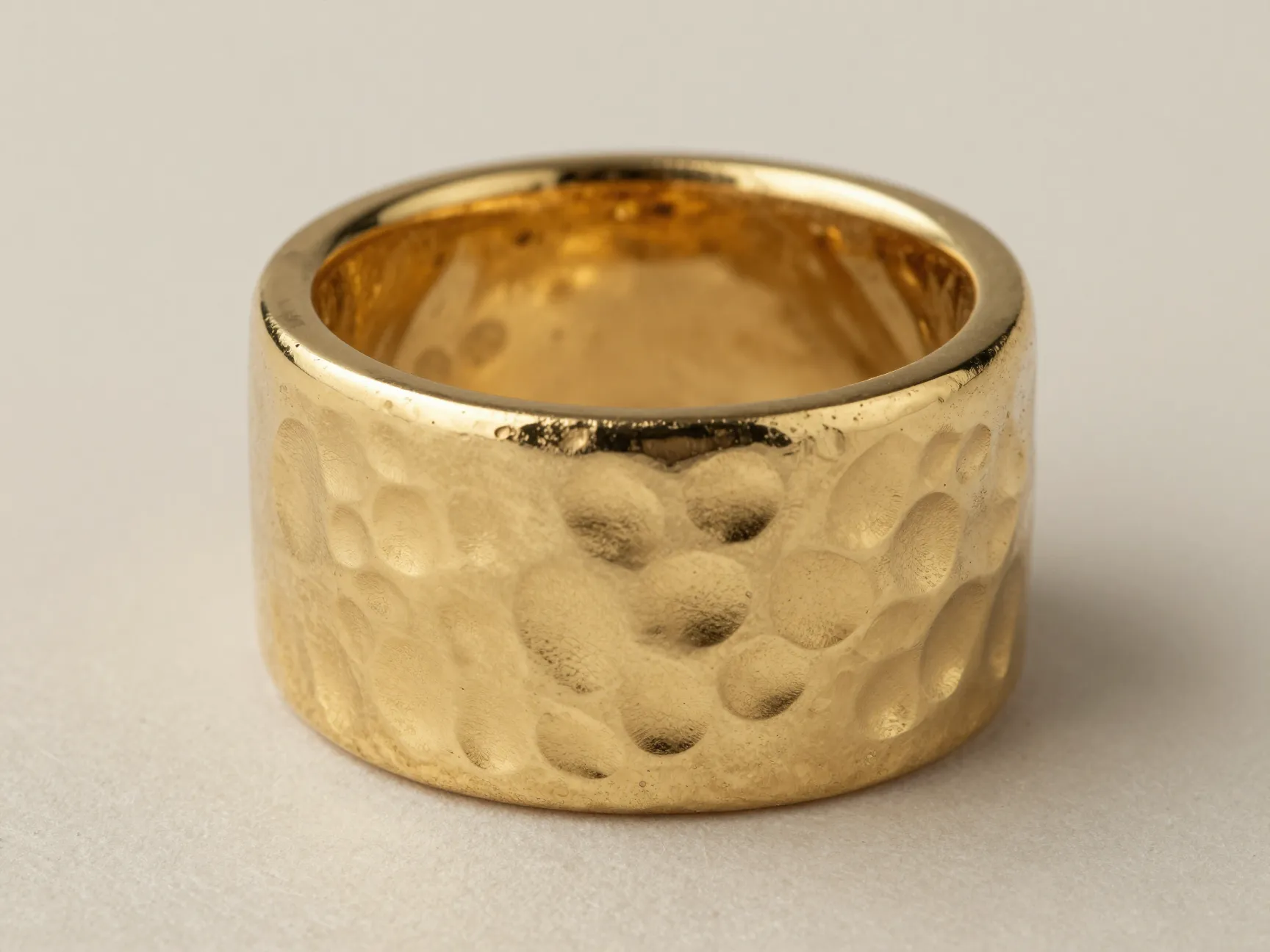 Wide hammered yellow gold sculptural band flat lay