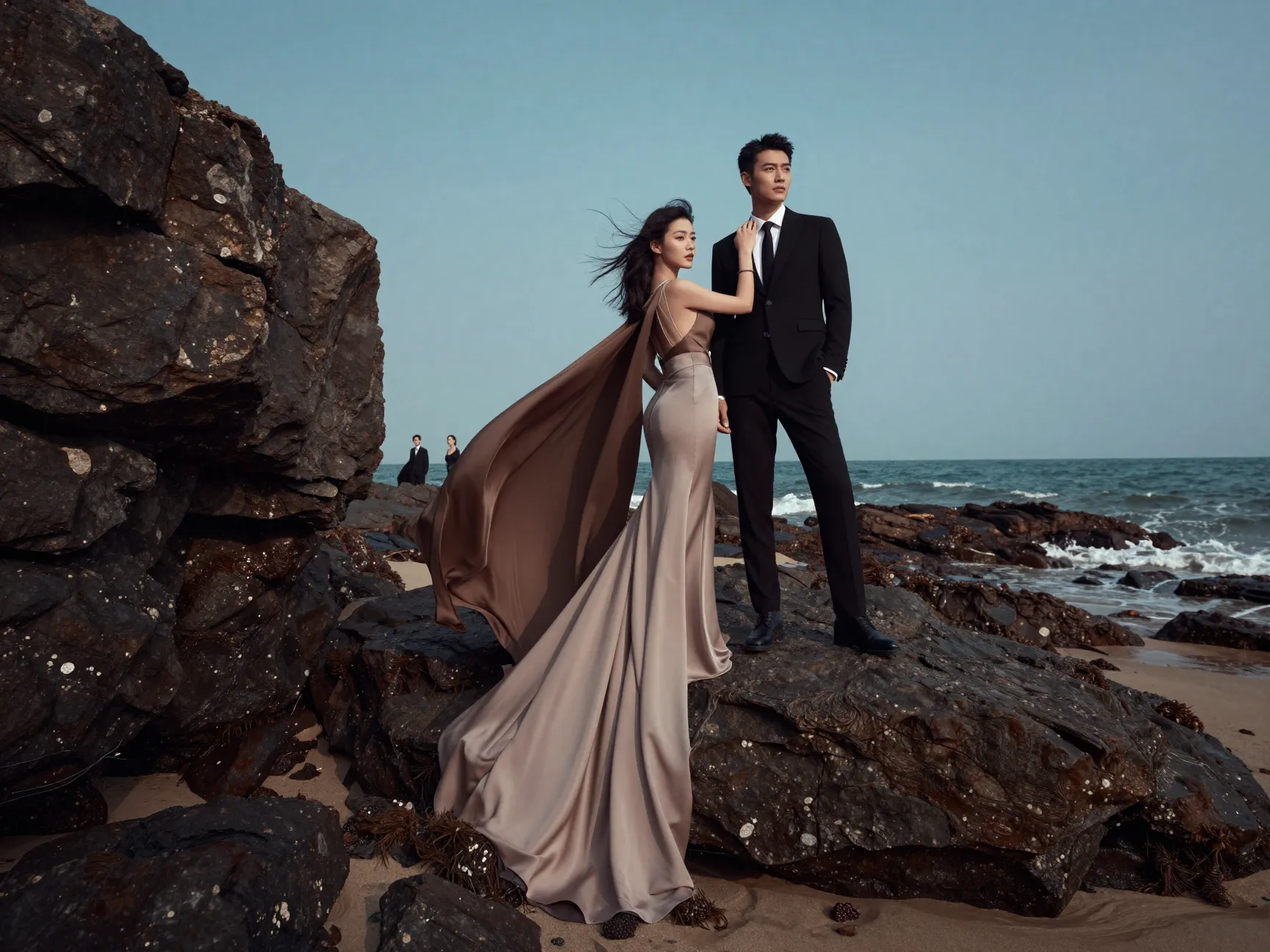 Fashion forward couple in editorial pose on rocky beach outcrop
