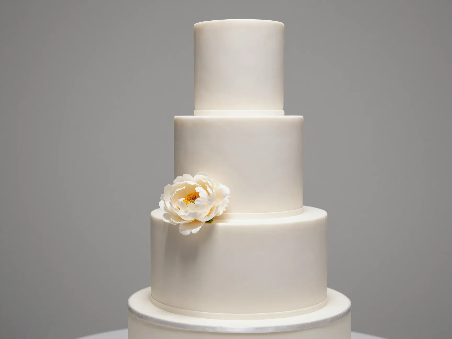 Smooth matte fondant wedding cake with single fresh peony accent