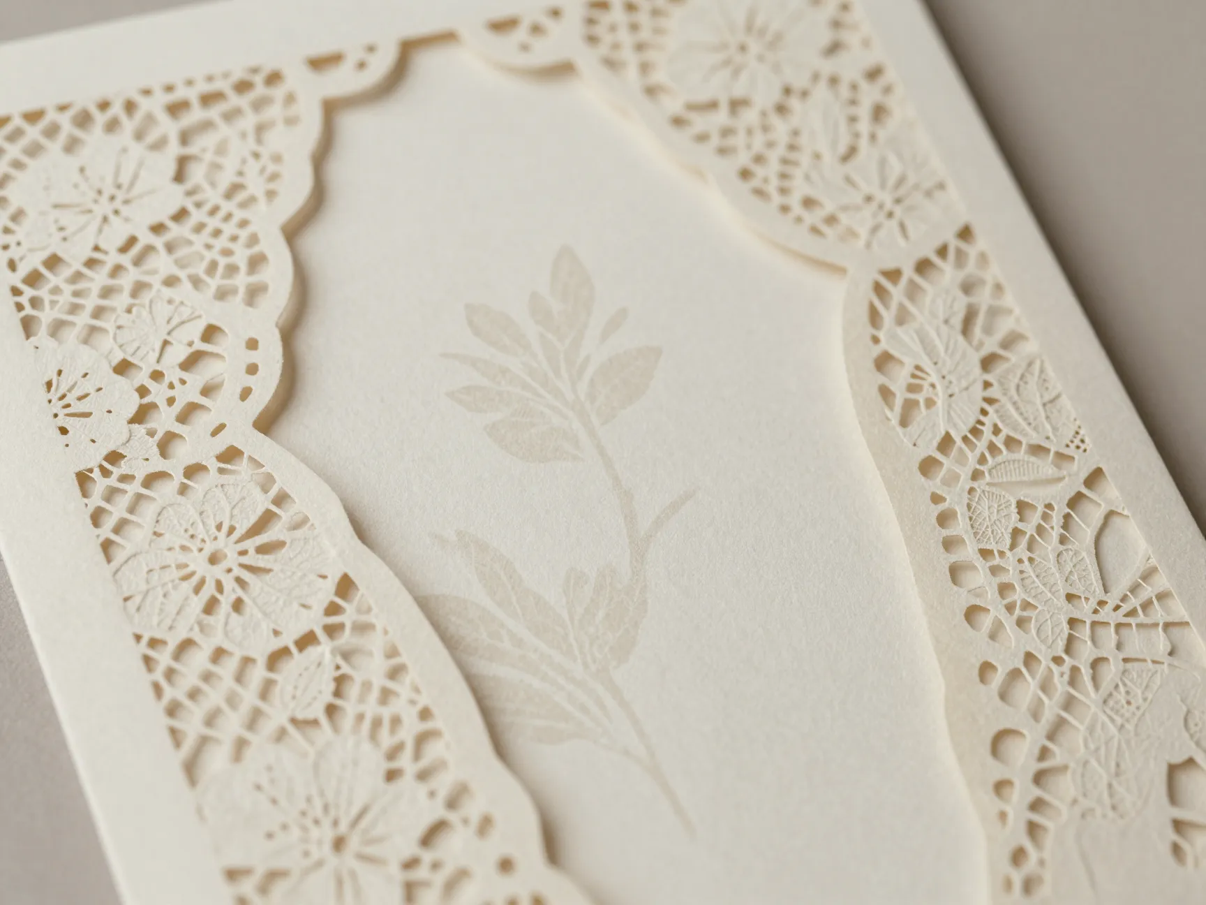 Laser cut lace paper jacket over cream botanical invitation