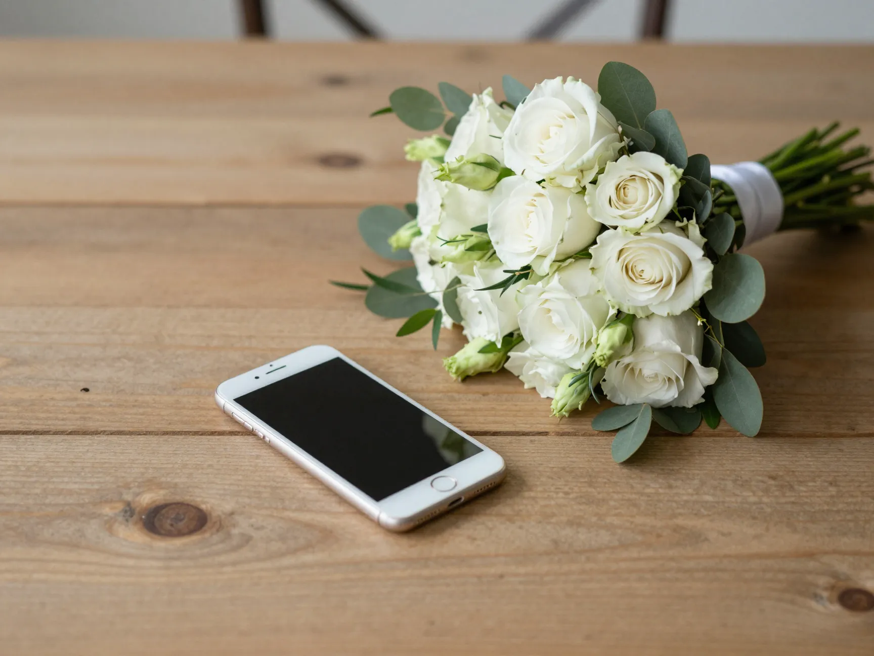 Phone facedown next to simple elegant bridal bouquet still life