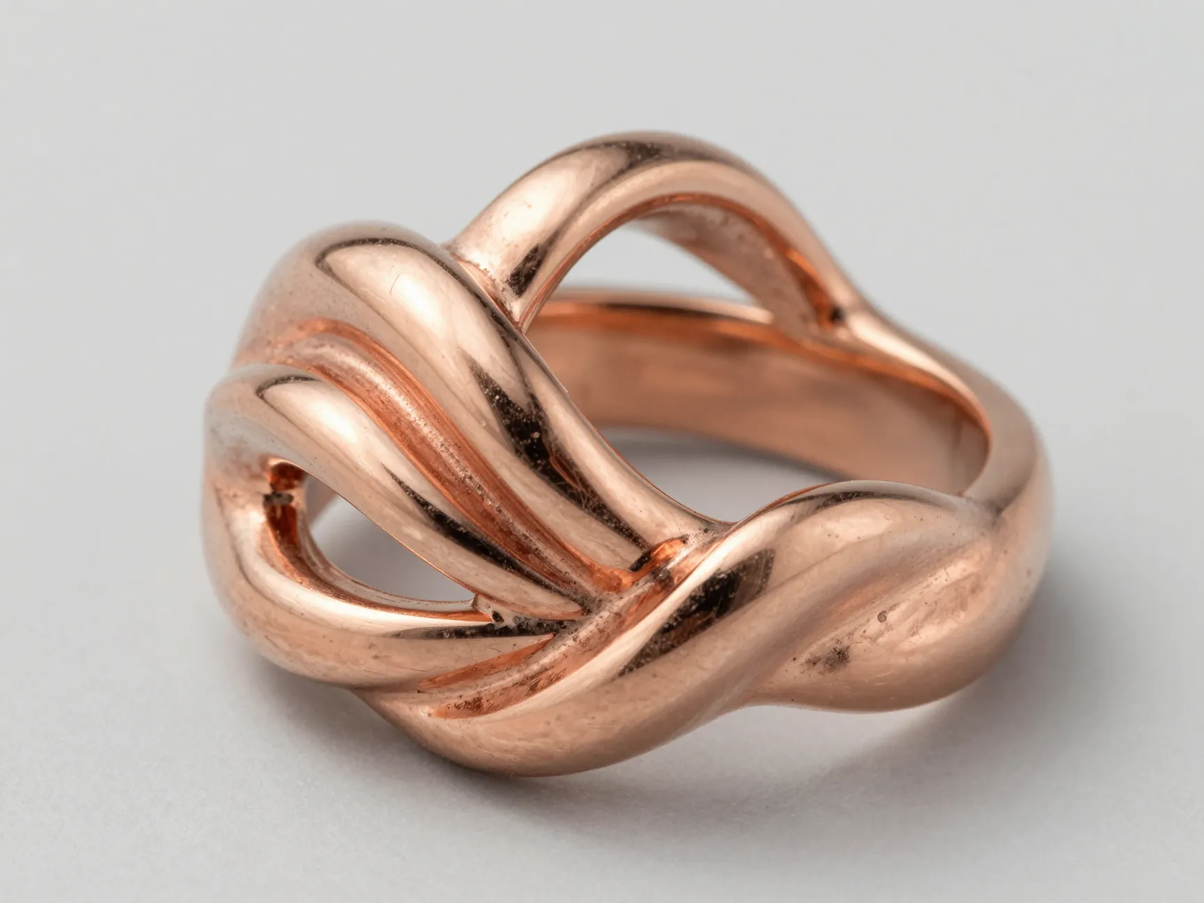 Sculptural rose gold wedding band with twisted metal detailing