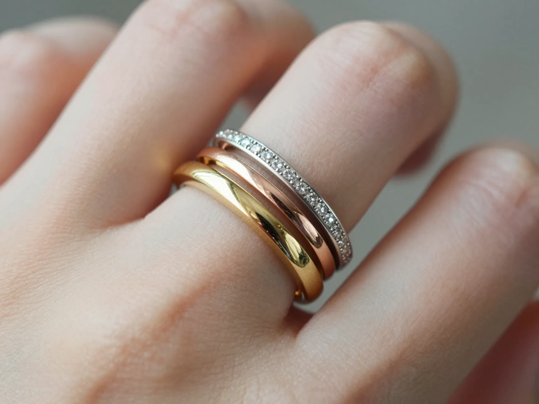 Stackable wedding bands in yellow rose and white gold layered on finger