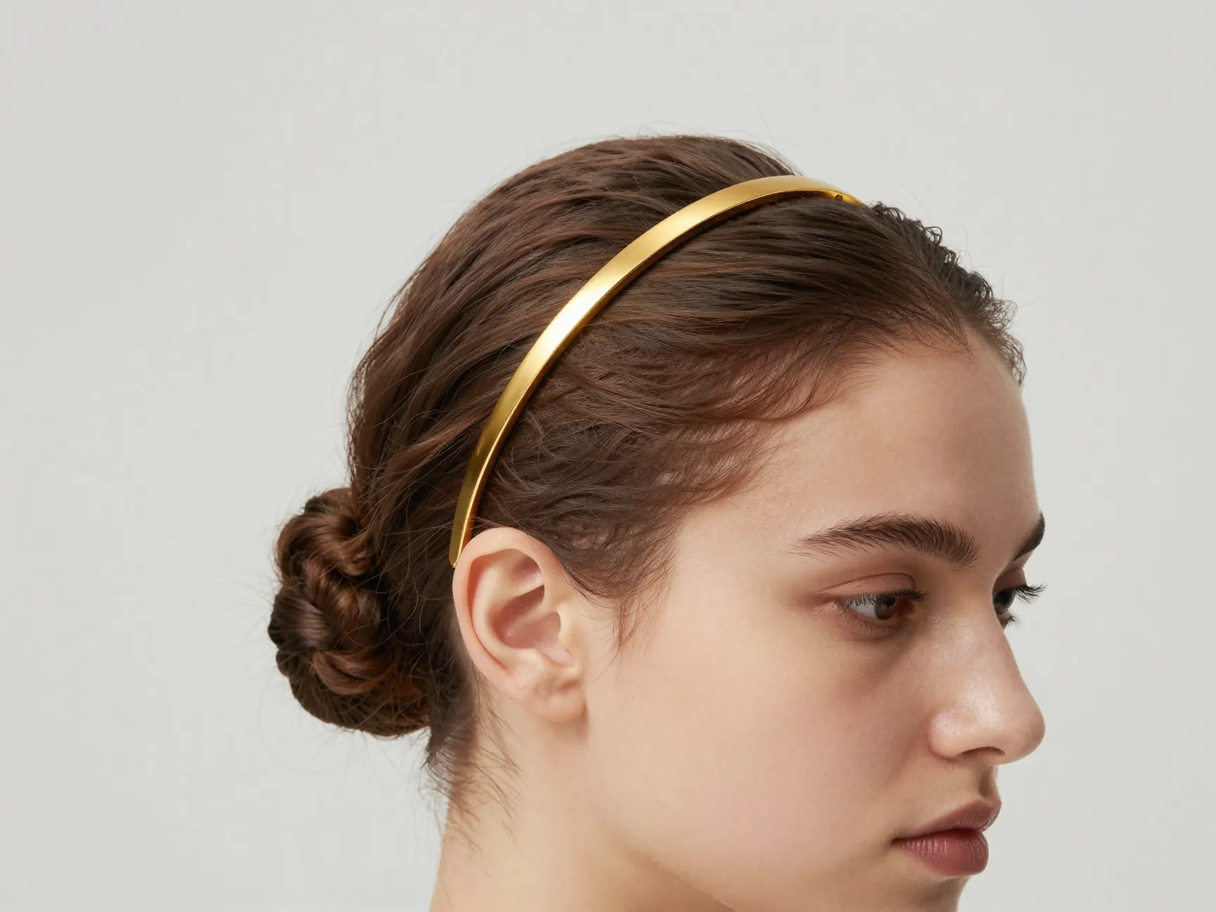 Thin polished gold headband with refined textured low bun
