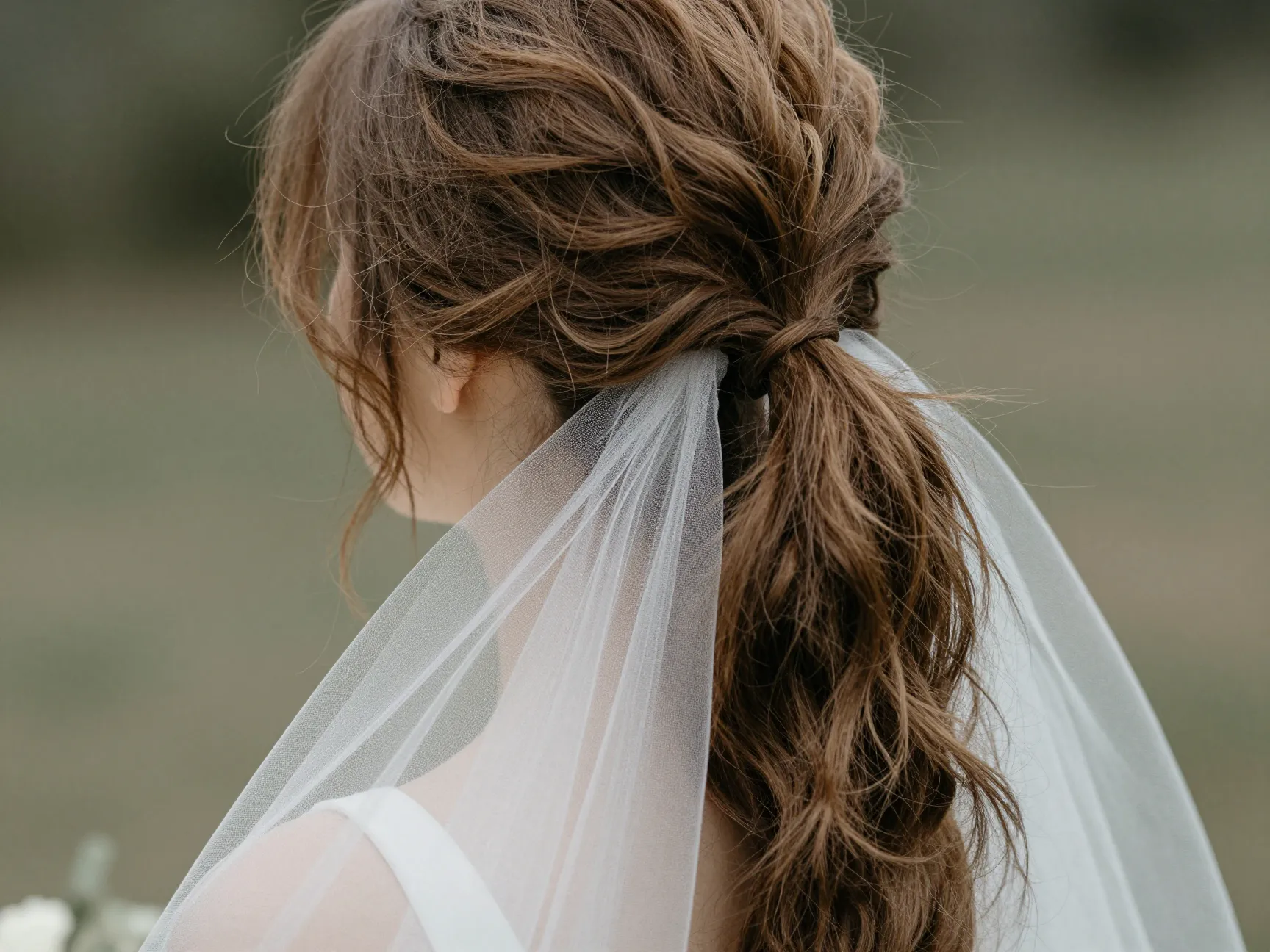 Textured low ponytail with face framing tendrils soft veil