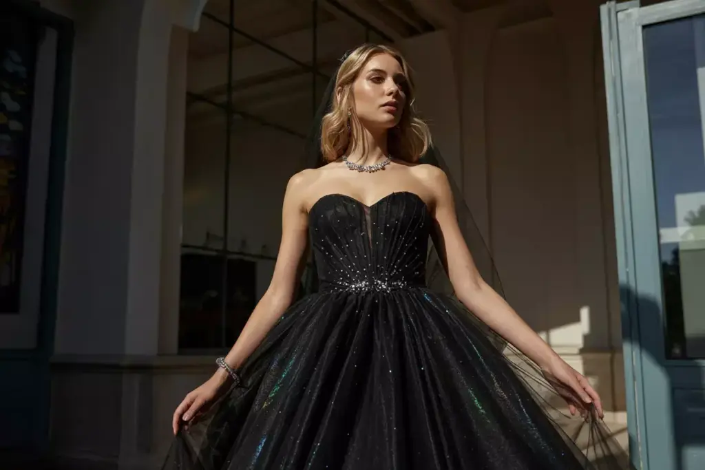 Woman in a strapless, sparkling black ball gown standing outside, looking confident and elegant.