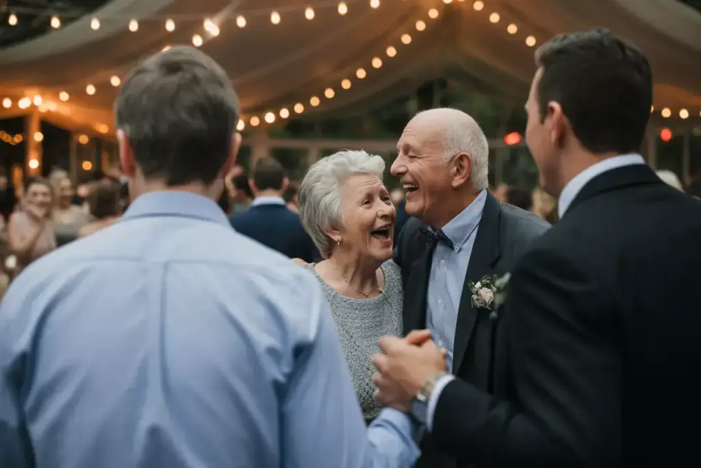 An elderly couple laughs and dances together at a festive, warmly lit outdoor party.