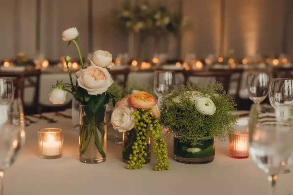 Elegant table setting with candles and floral centerpieces featuring roses and greenery.