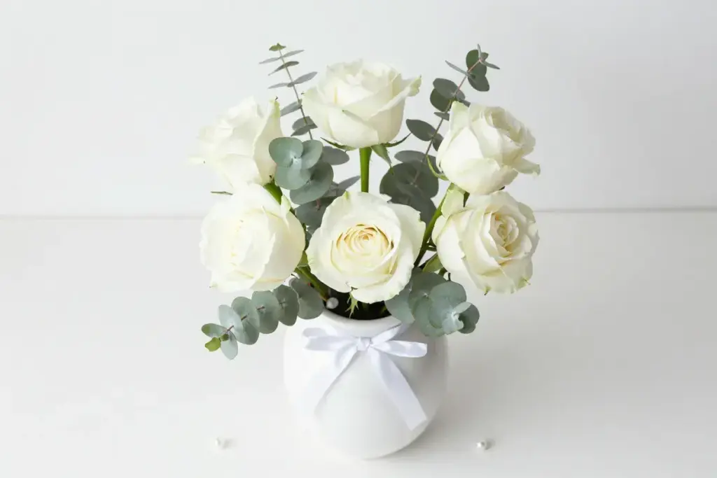 Five white roses eucalyptus white ceramic vase serenity