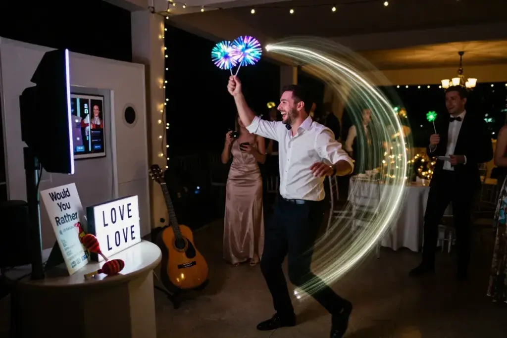 Guest using light up led pom pom props at evening wedding reception