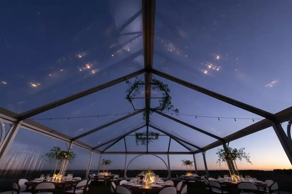 Modern clear top tent revealing starry night sky above minimalist tables