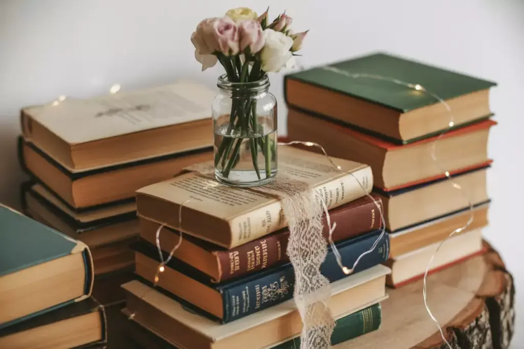 Vintage book stack with glass vase of fresh flowers and fairy lights