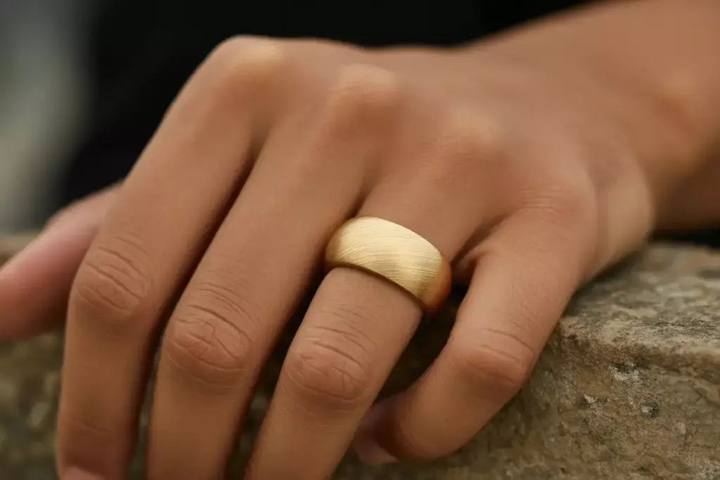 18k gold brushed finish band on hand textured surface