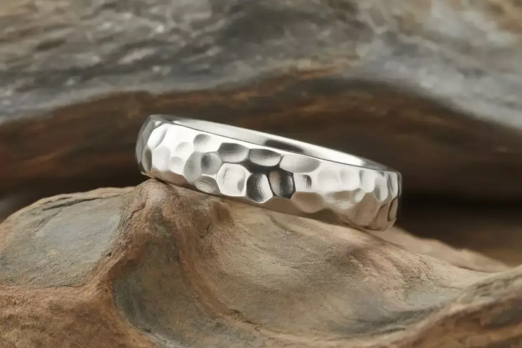 Hammered texture platinum band on organic surface closeup