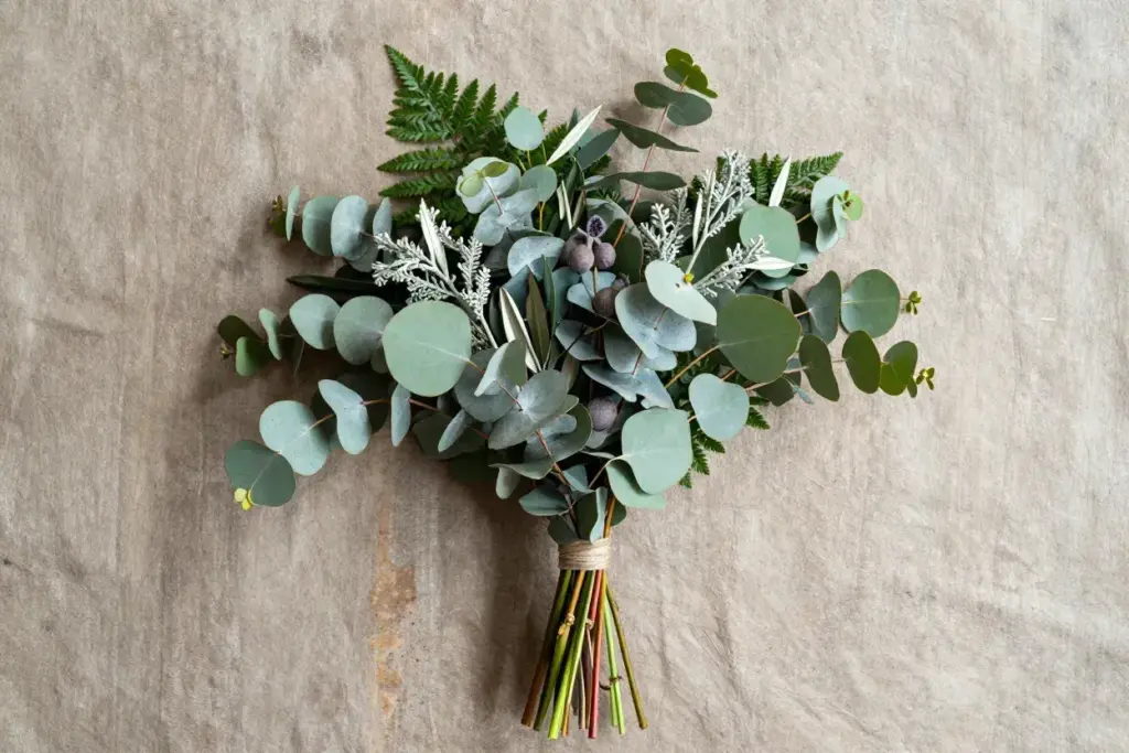 Natural eucalyptus and mixed greenery bouquet flat lay on textured slate