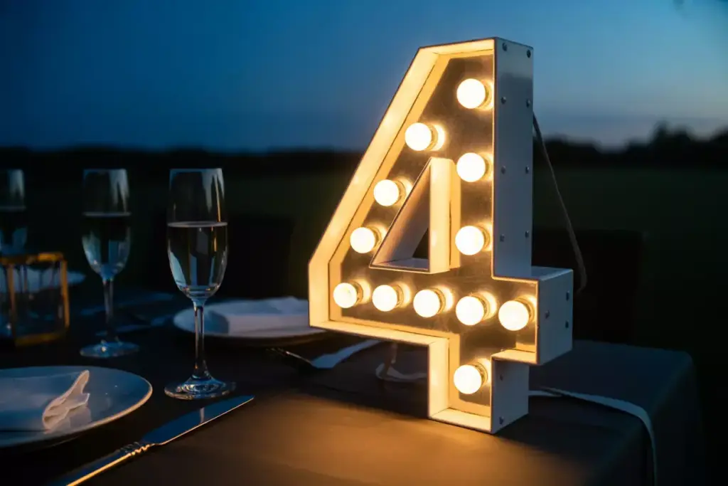 Glowing vintage marquee number four on dark table at dusk