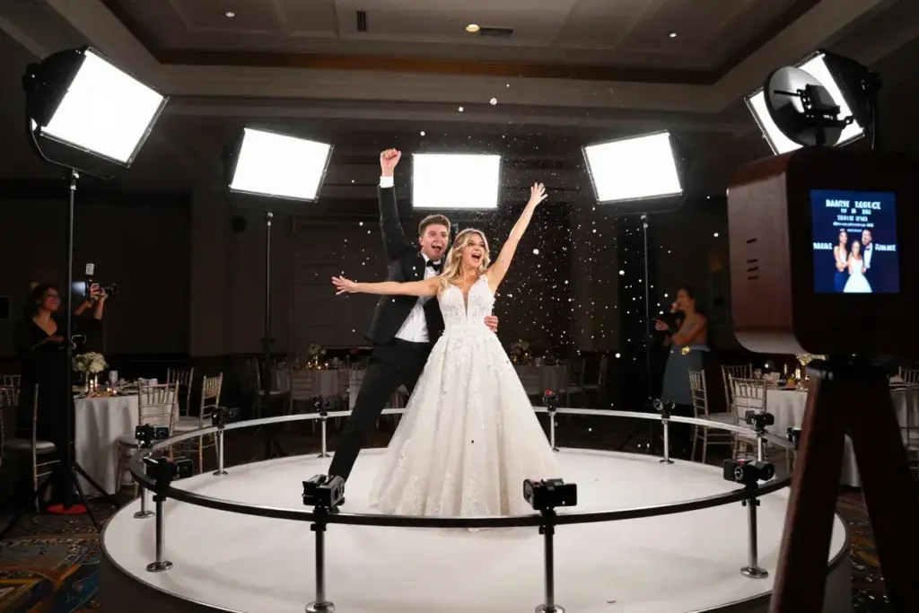 Couple celebrating on spinning 360 photo booth platform with confetti and cameras