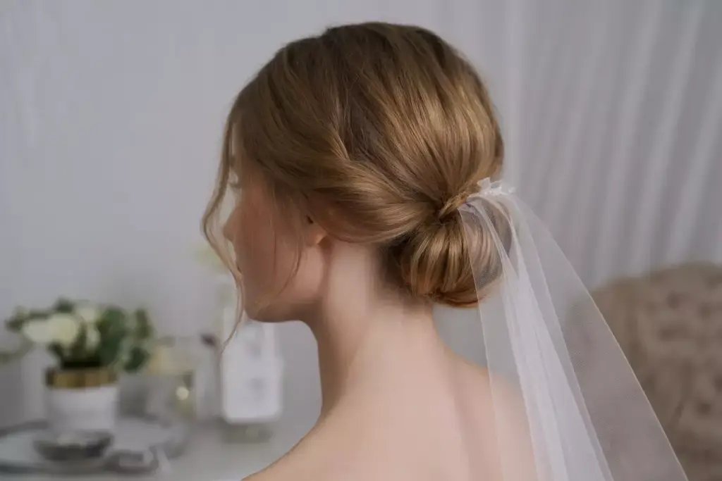 Romantic low chignon with veil and face framing wisps