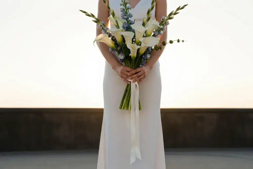 Bride cradling arm sheaf bouquet outdoor garden ceremony