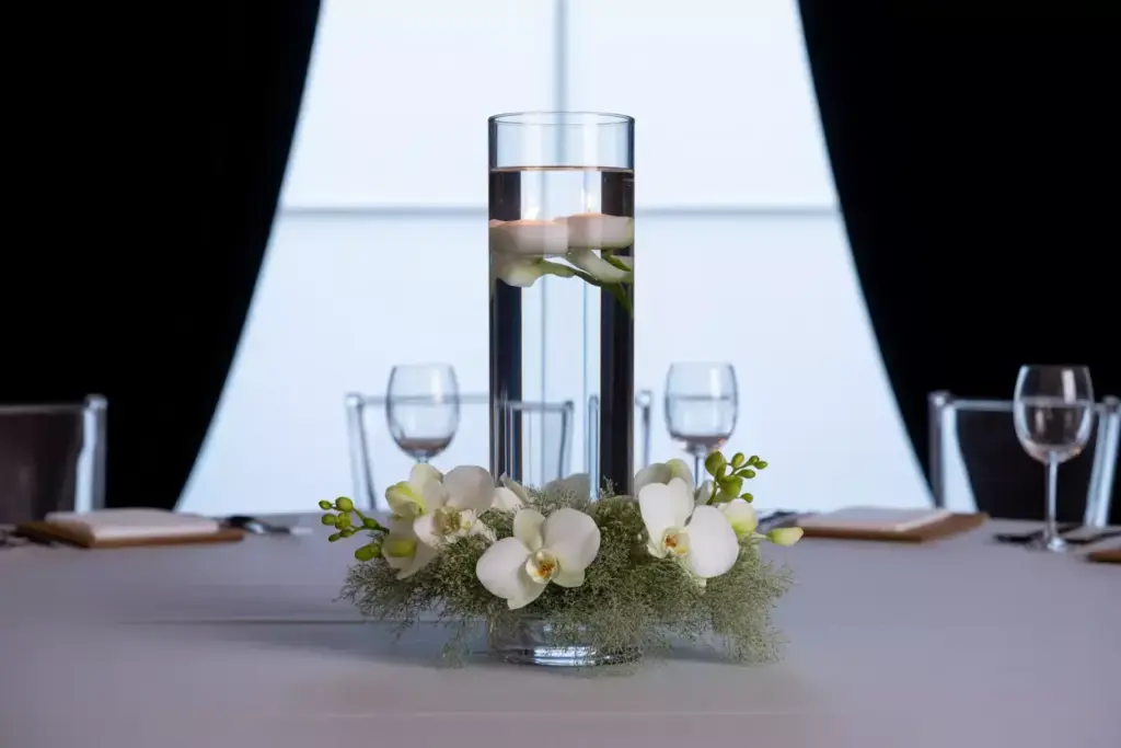 Tall glass cylinder with floating candle and white orchids
