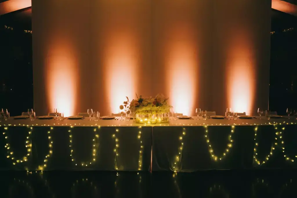 Head table with amber uplighting fairy lights and spotlight
