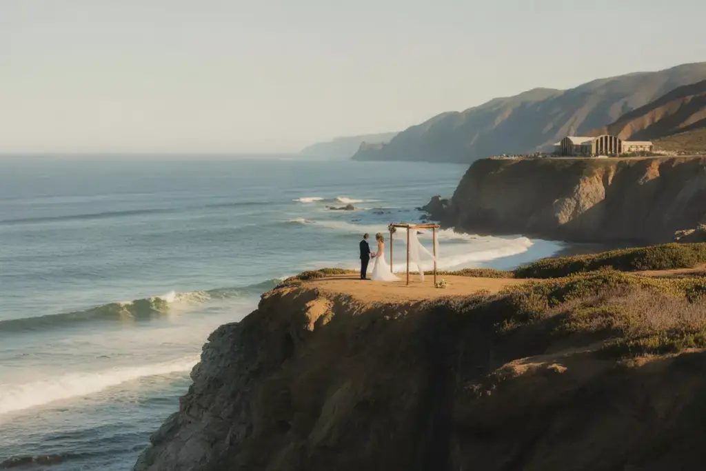 Couple marrying on dramatic clifftop overlooking pacific ocean