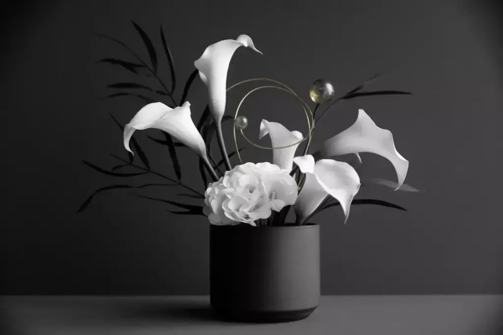Matte black vessel white silk flowers minimal greenery metallic accents monochromatic