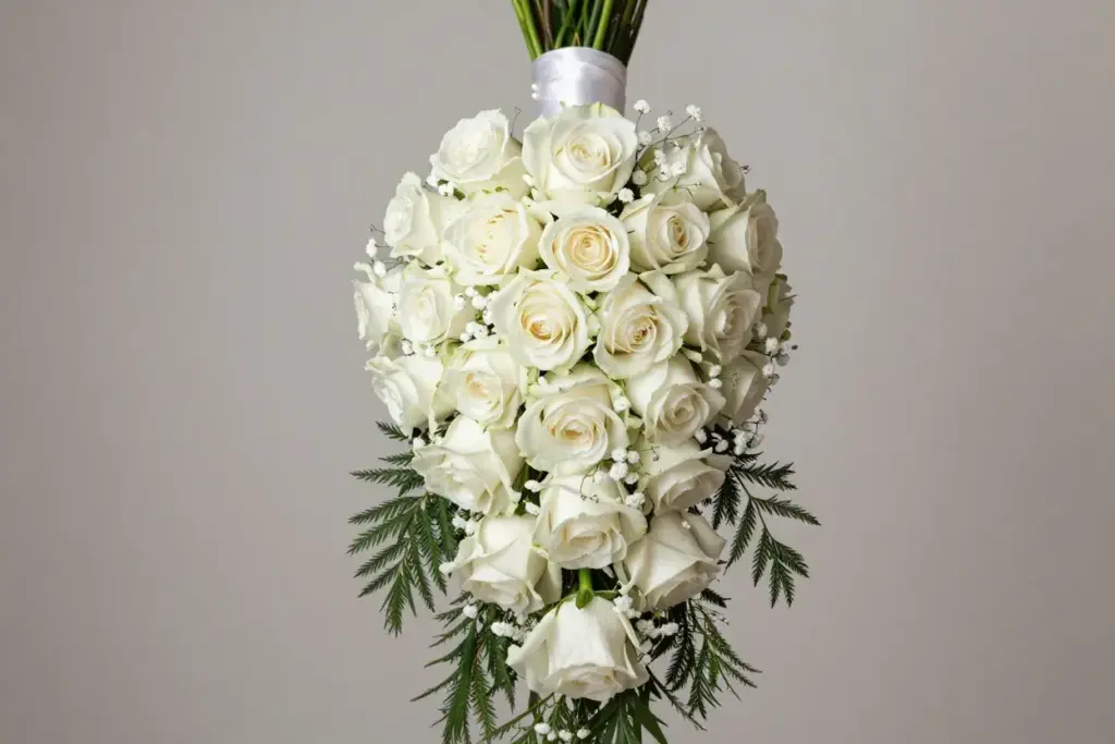 Elegant white rose cascade bouquet with pearl ribbon and greenery