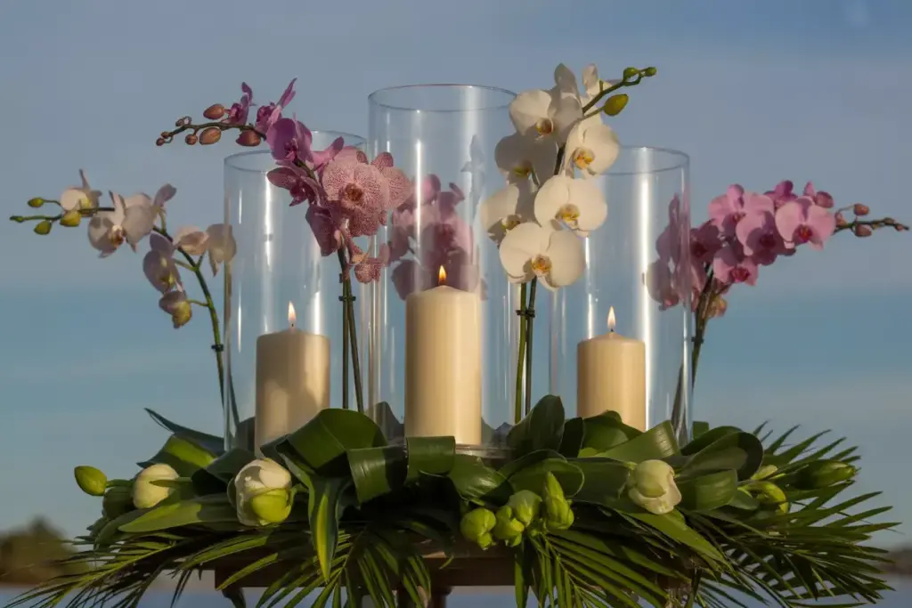 Dramatic lowangle orchids hurricane glasses pillar candles tropical greenery luxury centerpiece