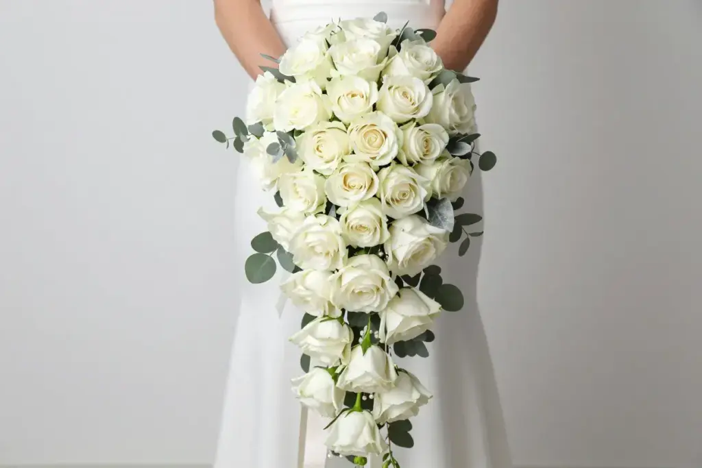 Overhead studio shot of white rose cascade bouquet with ivory ribbon