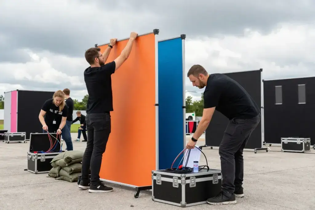 Team efficiently assembling modular photo booth using color coded parts