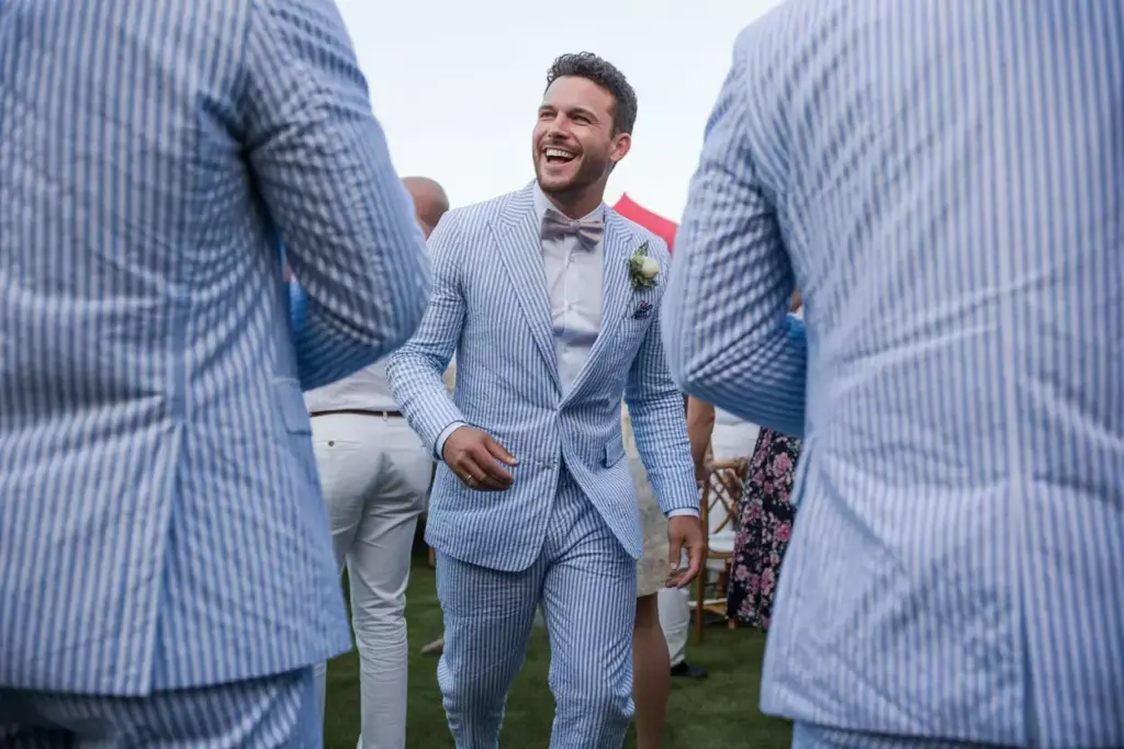 Blue white seersucker suit groom smiling outdoor summer reception