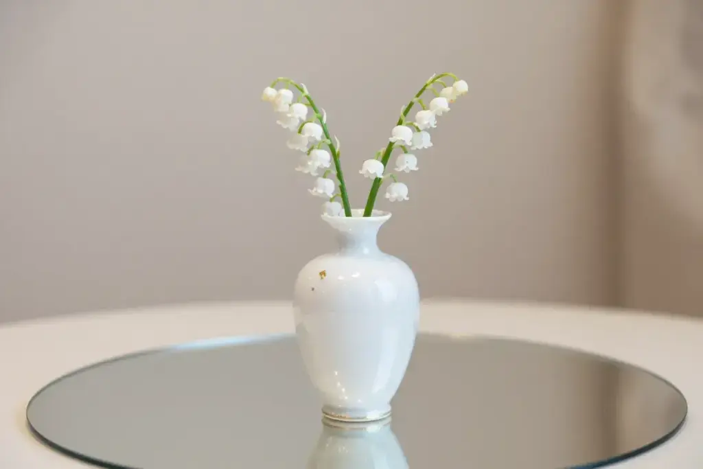 Delicate white porcelain bud vase lily of valley on mirror