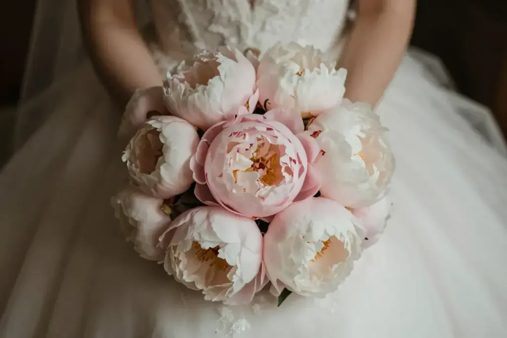 Lush pink peony bouquet against wedding dress fabric