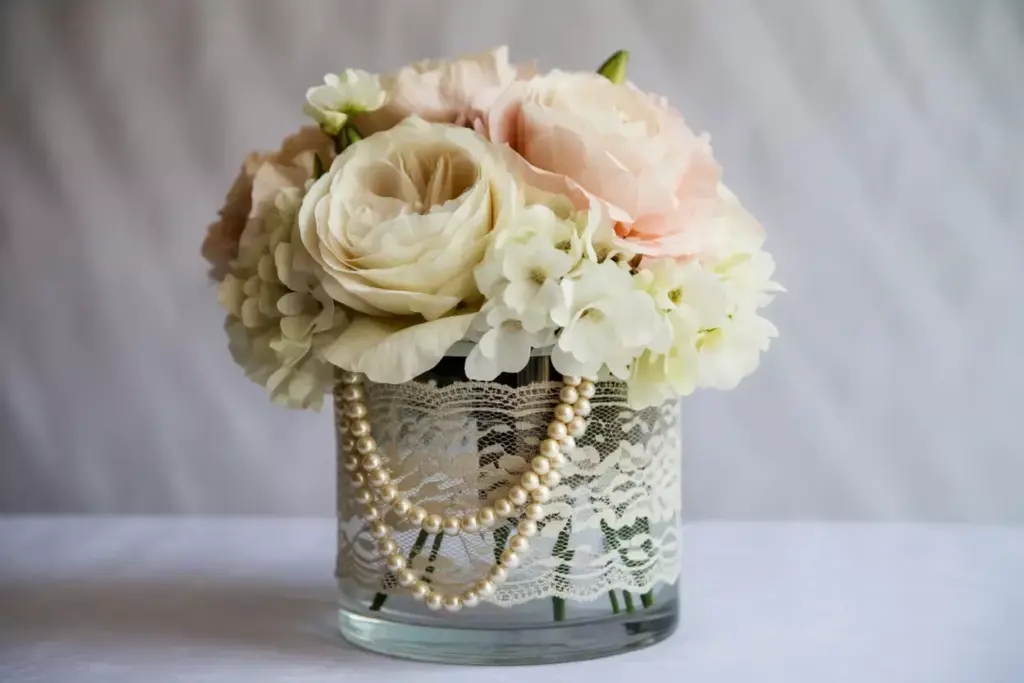 Tall lace wrapped vase with pearls and white peonies