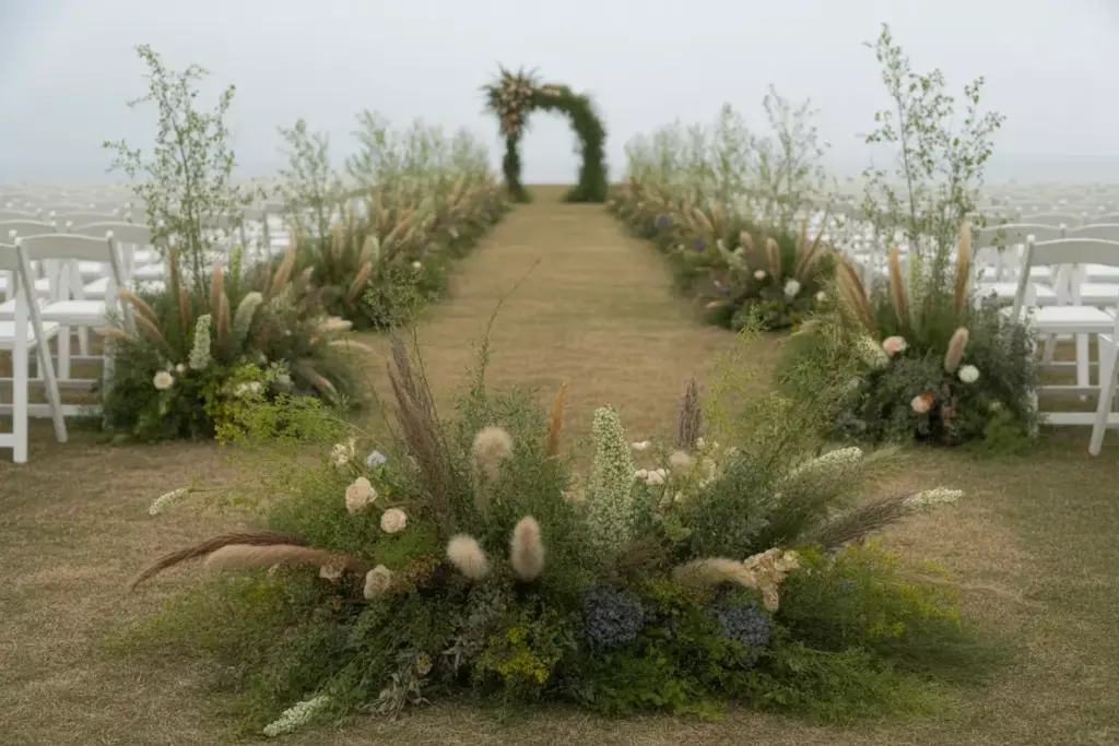 Sculptural ground level floral installation along outdoor ceremony aisle